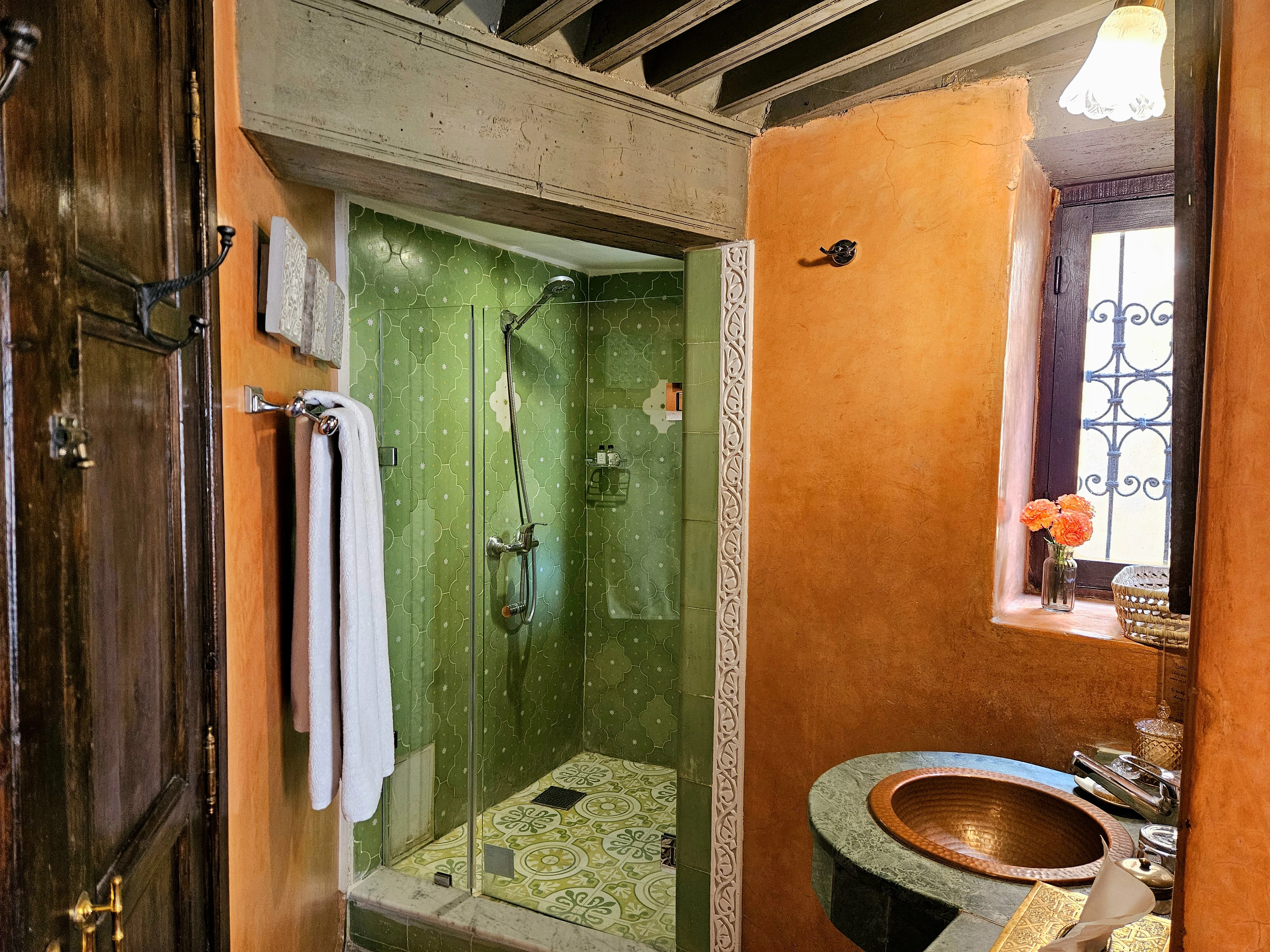 Private en-suite bathroom in Chambre Jade featuring a walk-in shower with emerald green Moroccan zellige tiles and copper washbasin