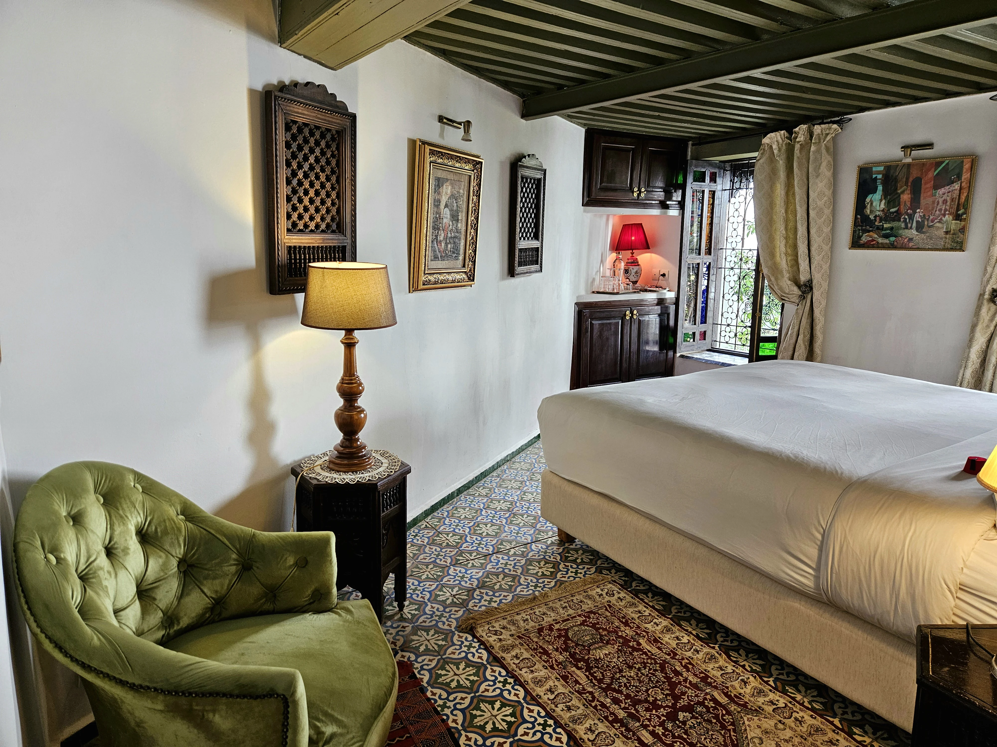 Bedroom view of Chambre Jade at Riad Le Calife showcasing wood-shuttered window overlooking the central riad courtyard patio