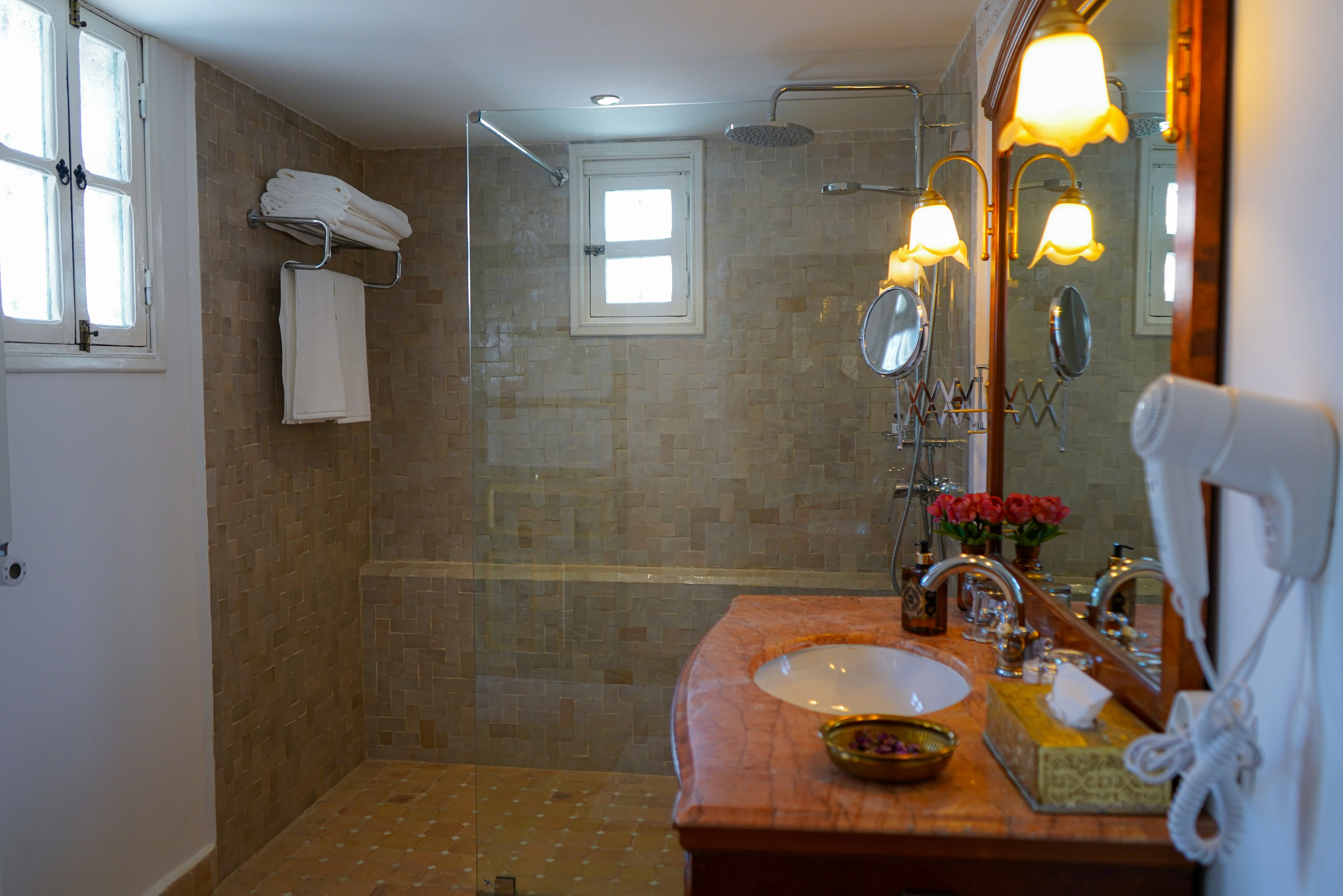 Private en-suite bathroom in Chambre Menzeh featuring walk-in sand-toned zellige shower, pink marble vanity, and luxury amenities