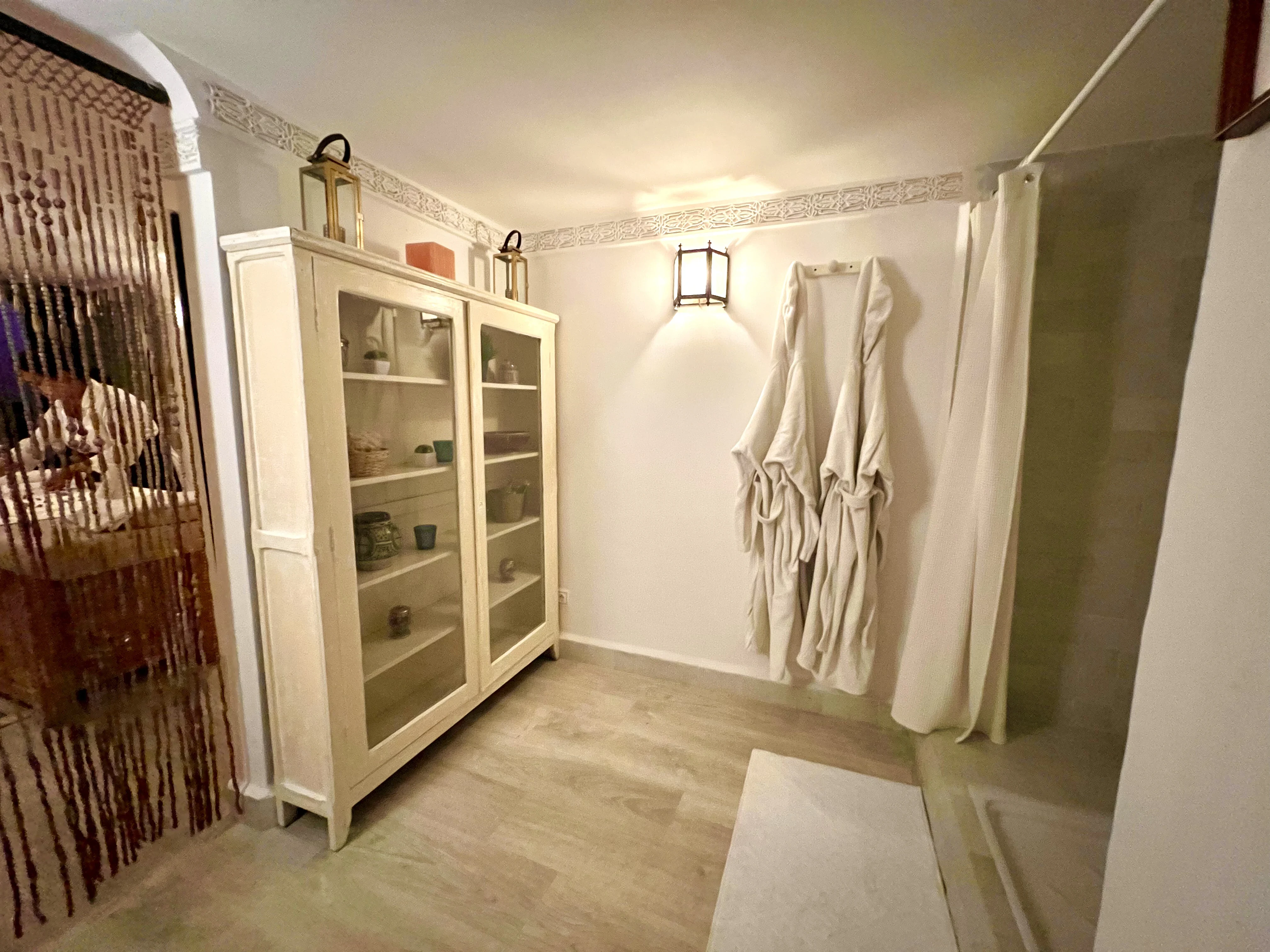 Dressing room with plush bathrobes and organic skincare showcase at Spa du Calife - Riad Le Calife